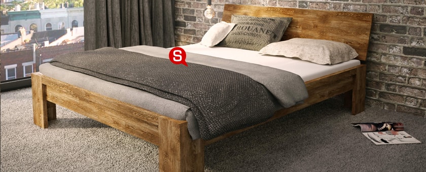 Kameralna sypialnia z drewnianym łóżkiem. Betonowa ściana i szare elementy doskonale wpasowują się w rustykalny klimat.